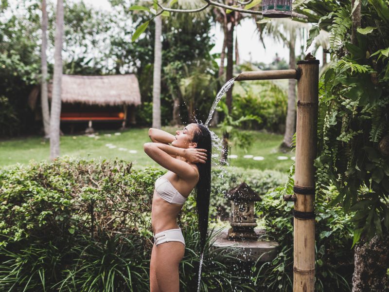 Girl in a bikini having a shower in an outdoor shower in Bali