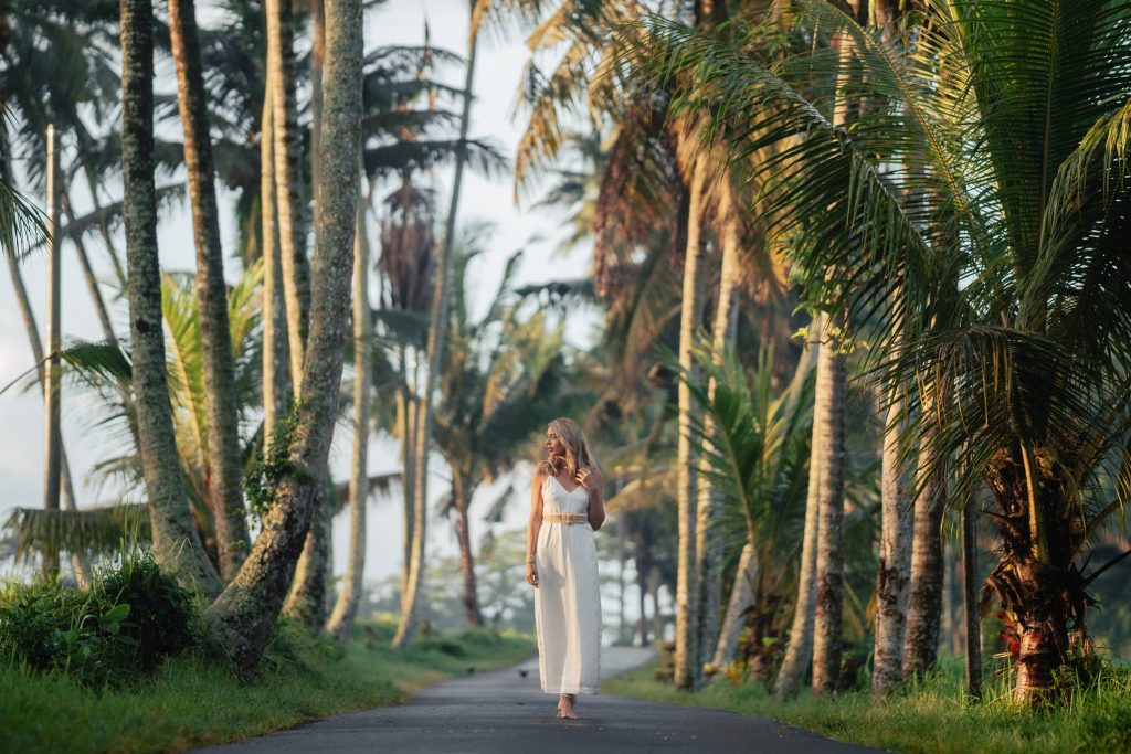 Blonde woman wearing all white walking through a serene path in Ubud Bali